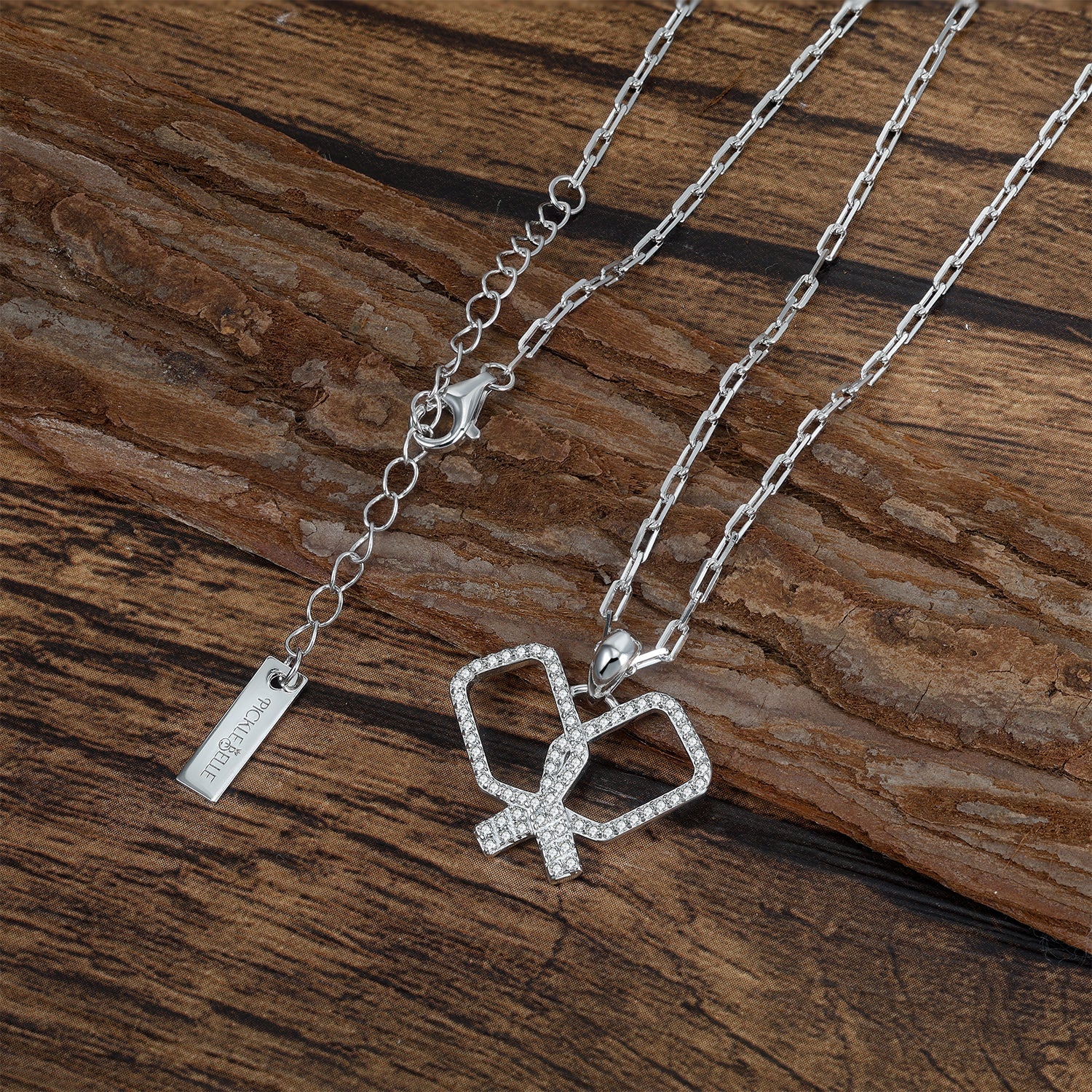 Silver necklace with a heart-shaped pickleball paddles pendant on a wooden surface