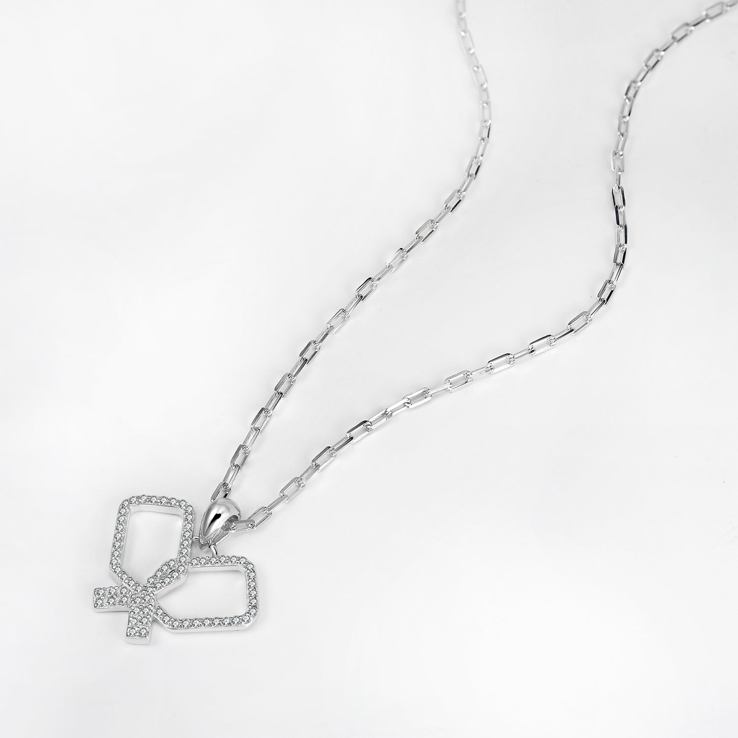Silver necklace with intersecting pickleball paddle pendant on a light gray background