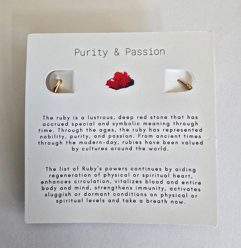 Pair of gold earrings on a card with 'Purity & Passion' text and ruby illustration.