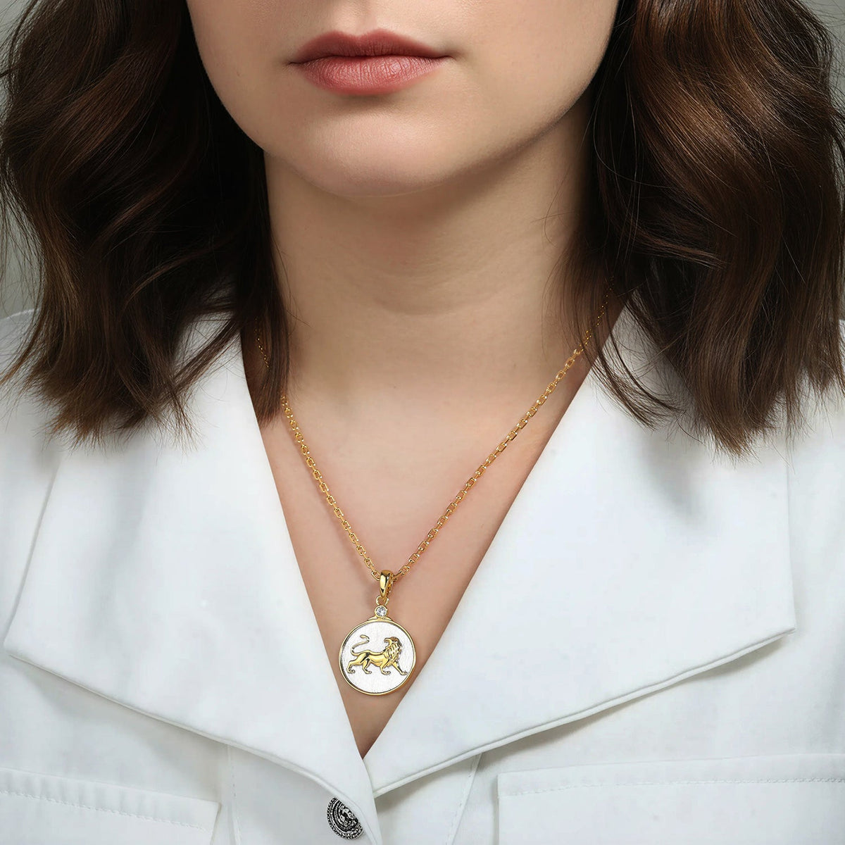 Woman wearing a gold necklace with a Zodiac Leo lion pendant on a white background