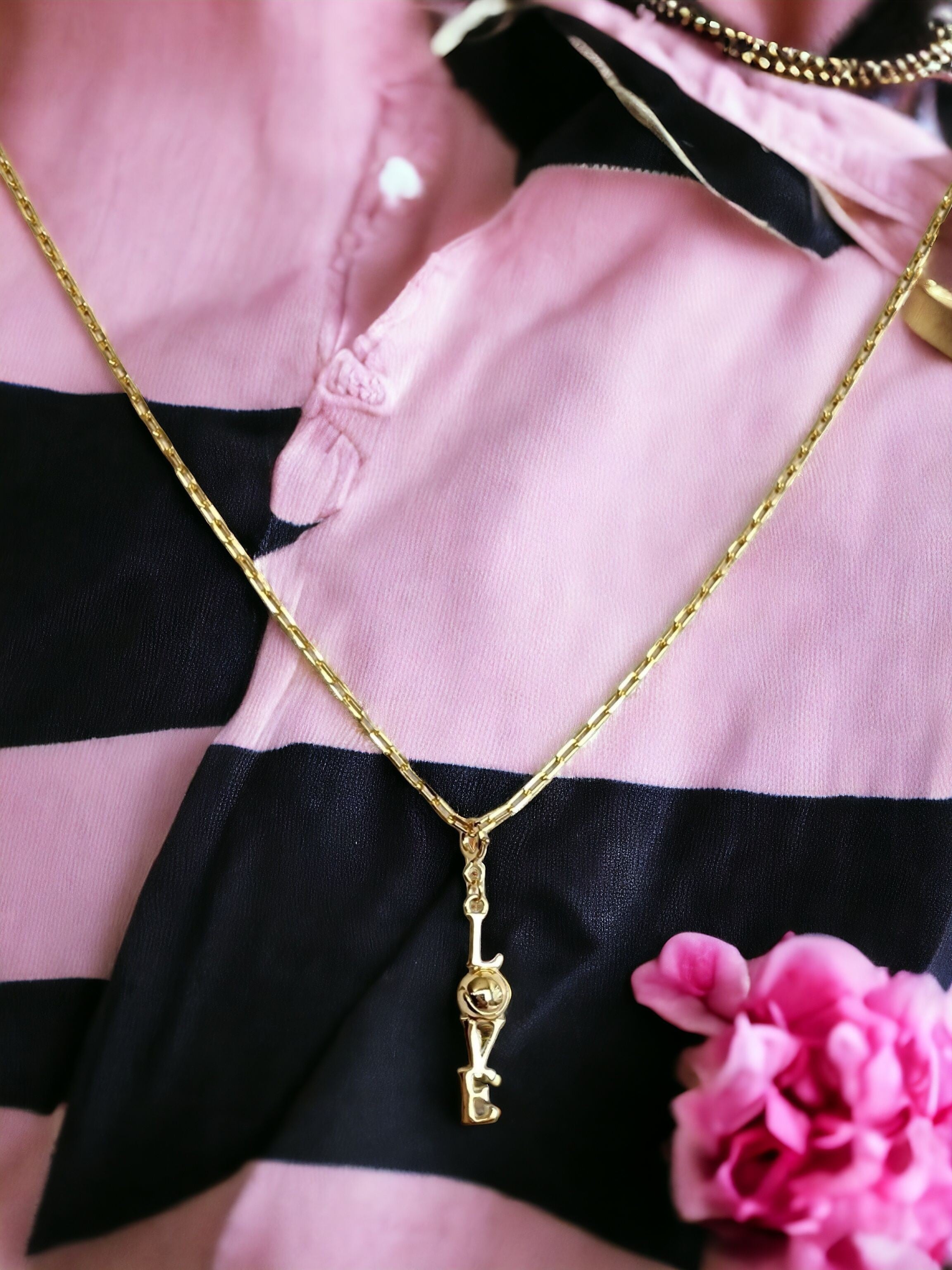 Gold Clip On Charm of the word "LOVE" shown on a gold chain