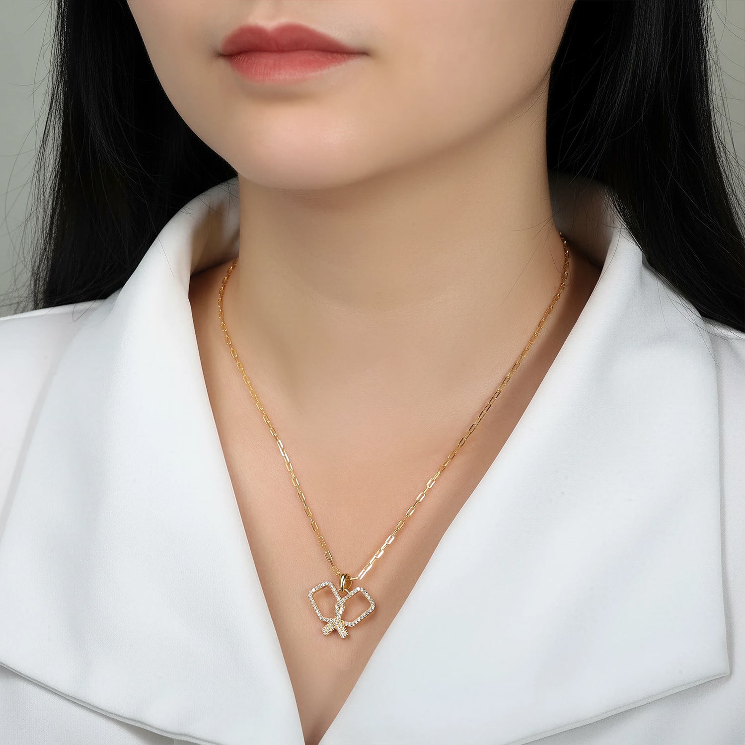 Gold necklace with criss cross crystal pickleball paddles pendant on a woman
