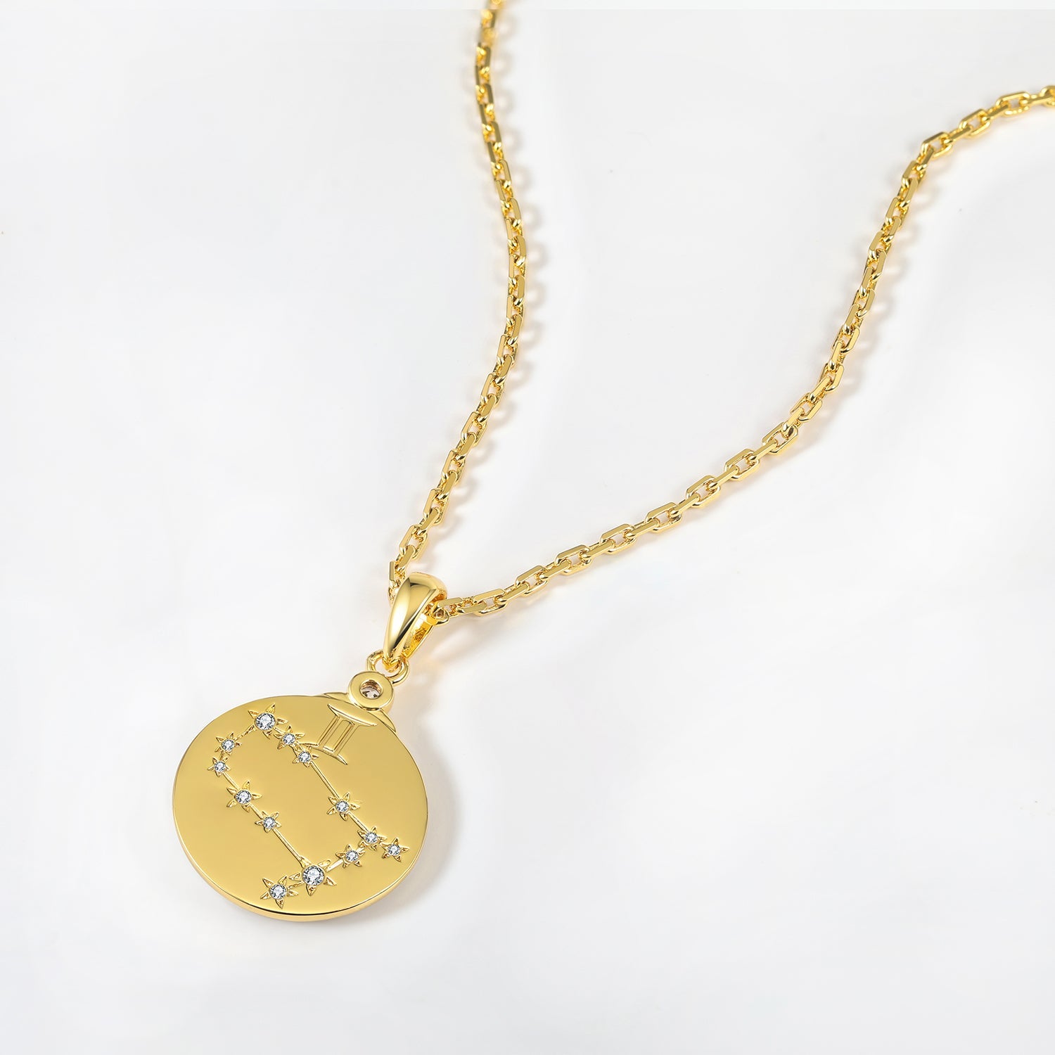 Gold necklace with a zodiac Gemini constellation pendant on a white background