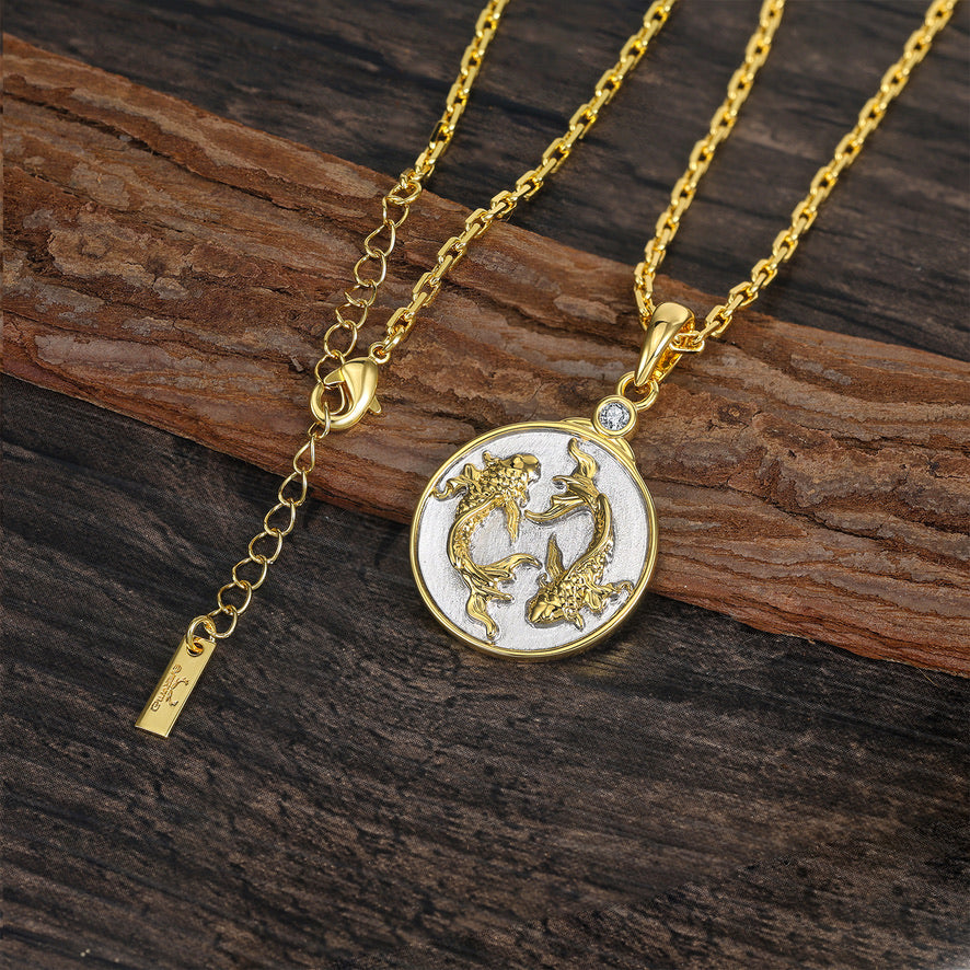 Gold chain necklace with a detailed Gold and Silver Pisces Zodiac pendant on a wooden surface