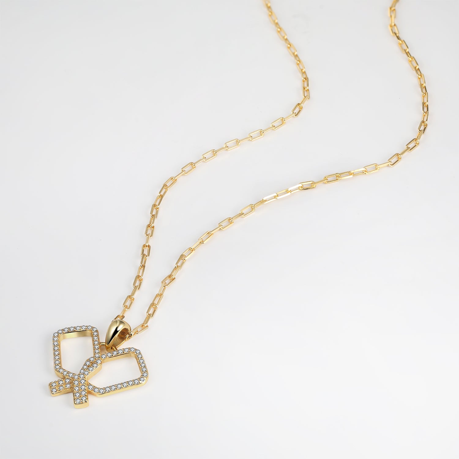 Gold necklace with criss cross crystal pickleball paddles pendant on a white background
