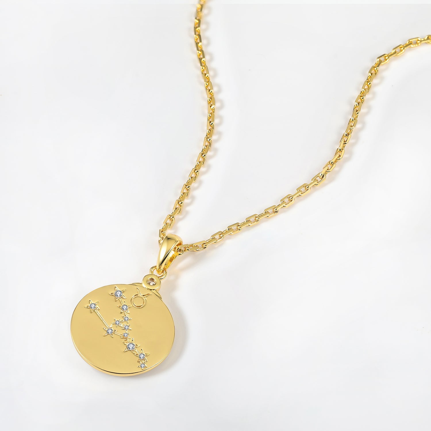 Gold necklace with a circular Taurus constellation pendant on a white background