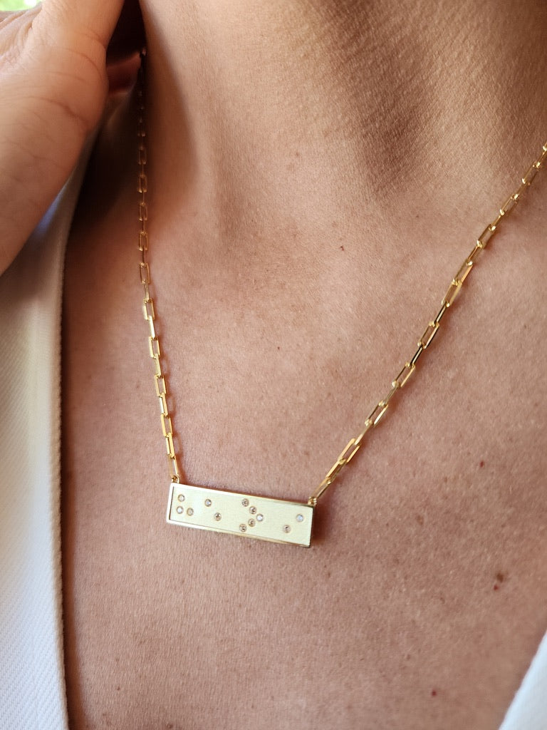 Gold Braille He > i necklace with a bar pendant on a person's neck