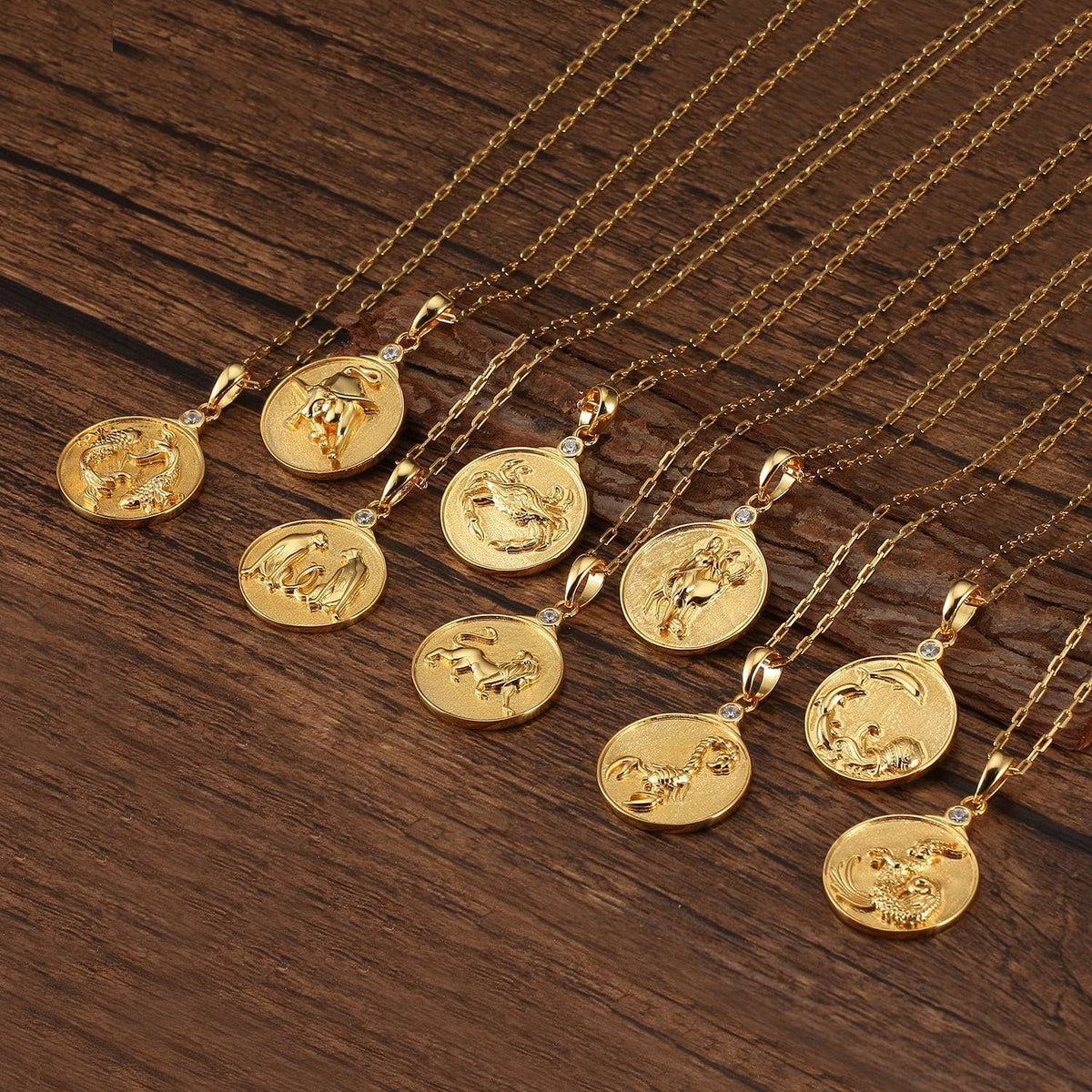 Grouping of various gold Zodiac Necklaces on wooden surface