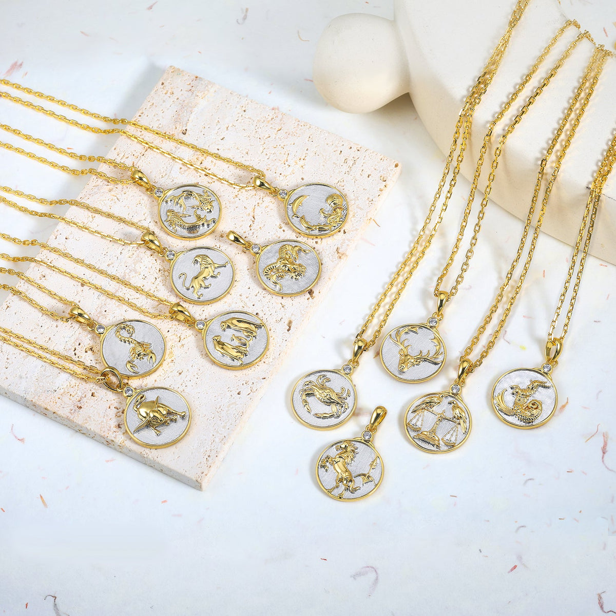 Gold necklaces with twelve Gold and Silver zodiac pendants on a white surface
