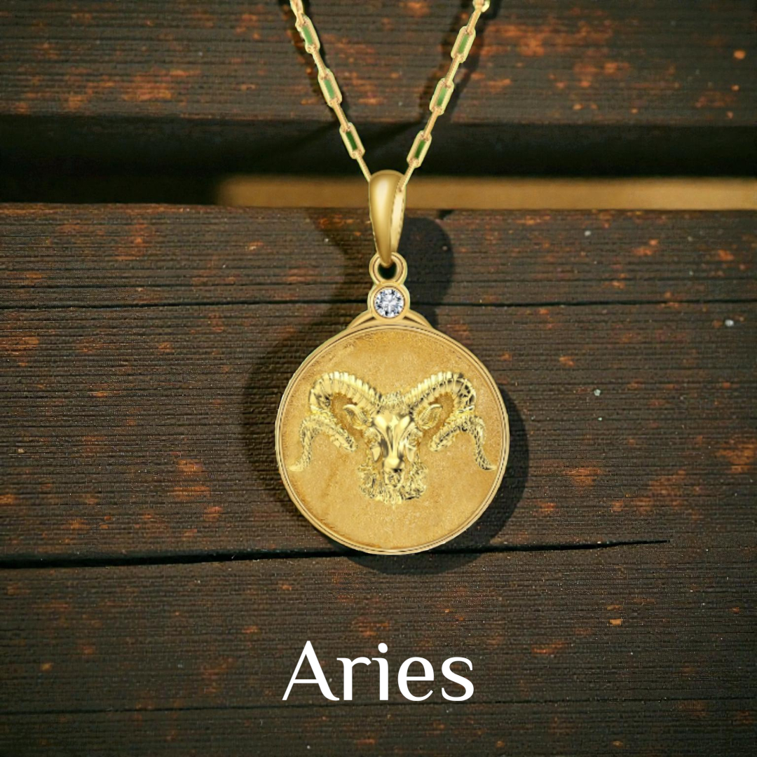 Gold Aries zodiac Ram pendant on a wooden surface with 'Aries' text below.