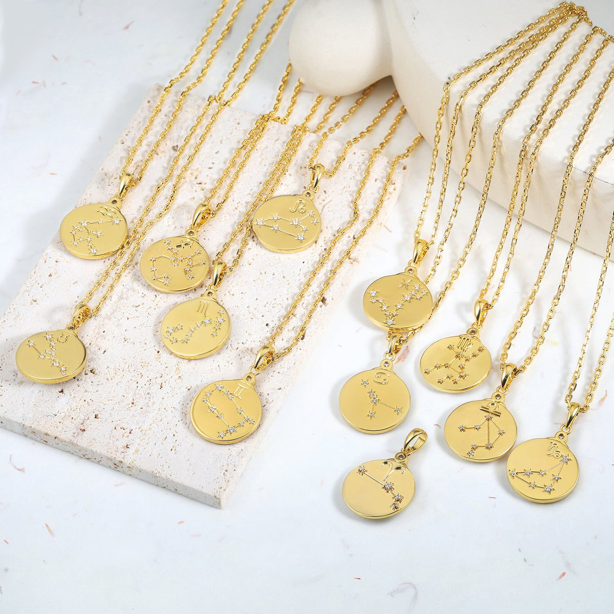 Gold necklaces with zodiac pendants on a white surface