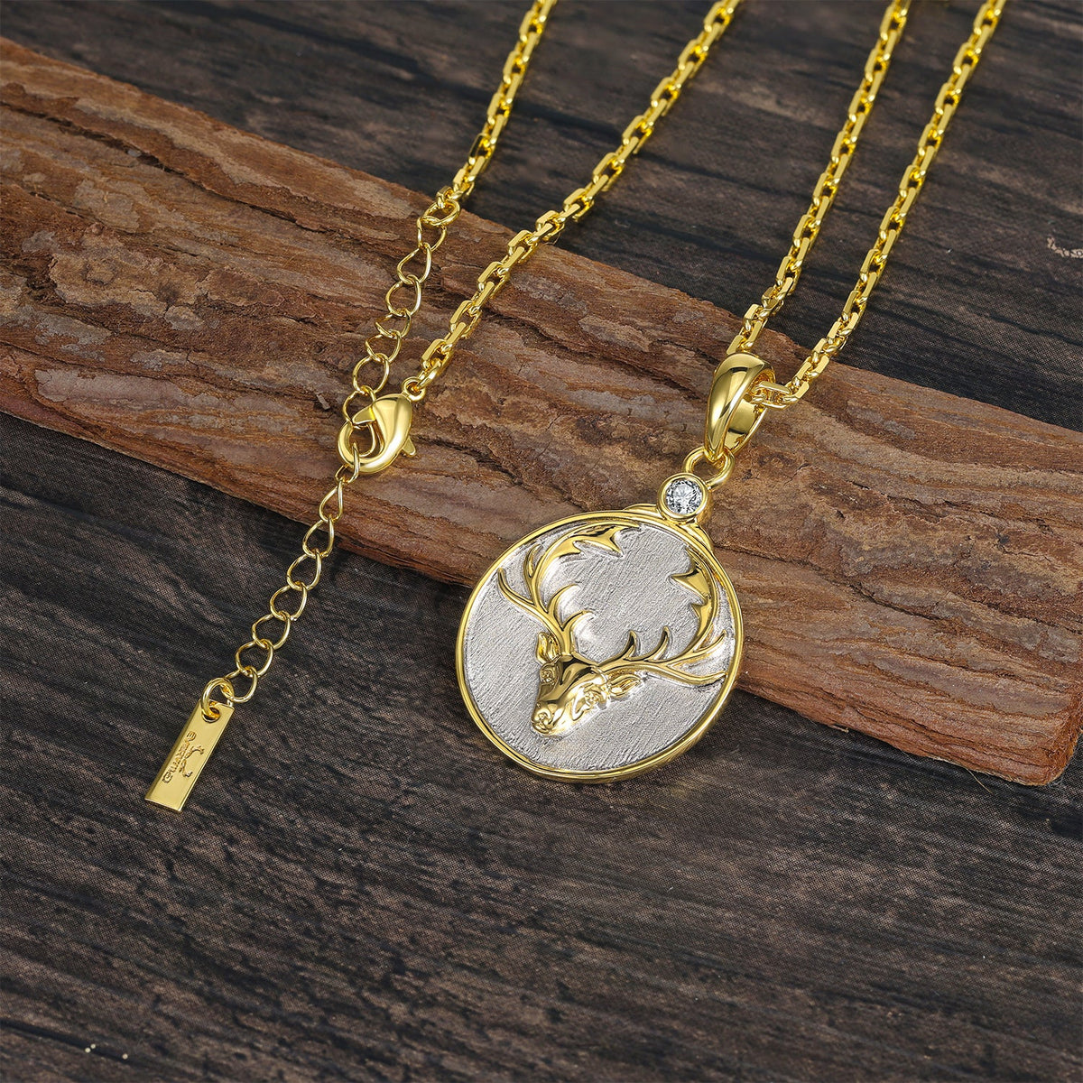Gold and silver necklace with a Virgo zodiac pendant with deer head on a wooden surface