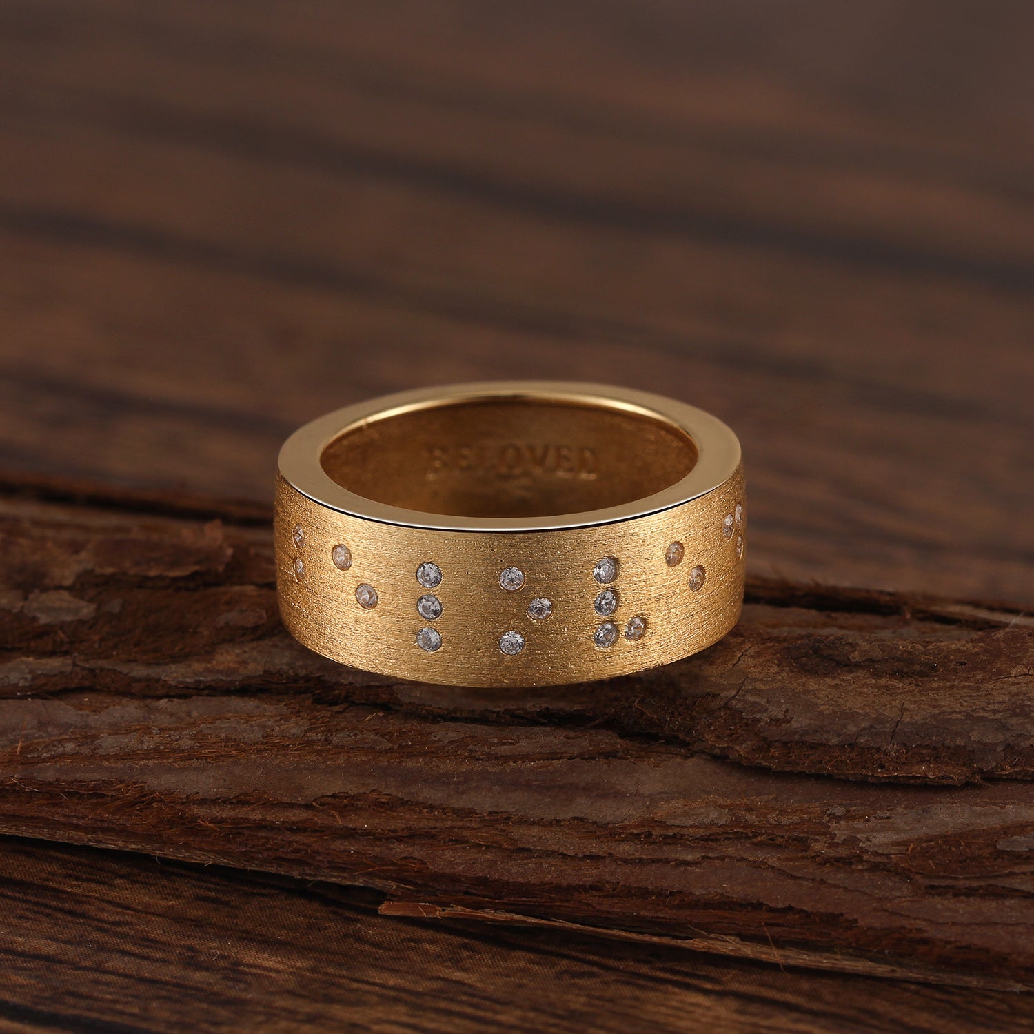 Touchstone Beloved Braille Crystals Band Ring Brushed Gold on Wooden Surface