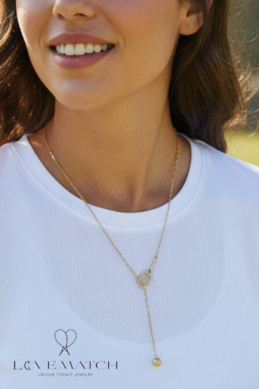 Woman wearing a gold Tennis Lariat necklace with a blurred background