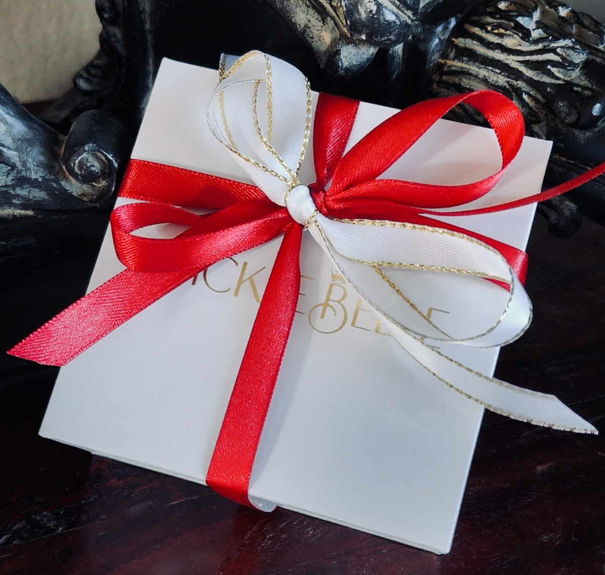 White gift box with a red ribbon on a dark surface