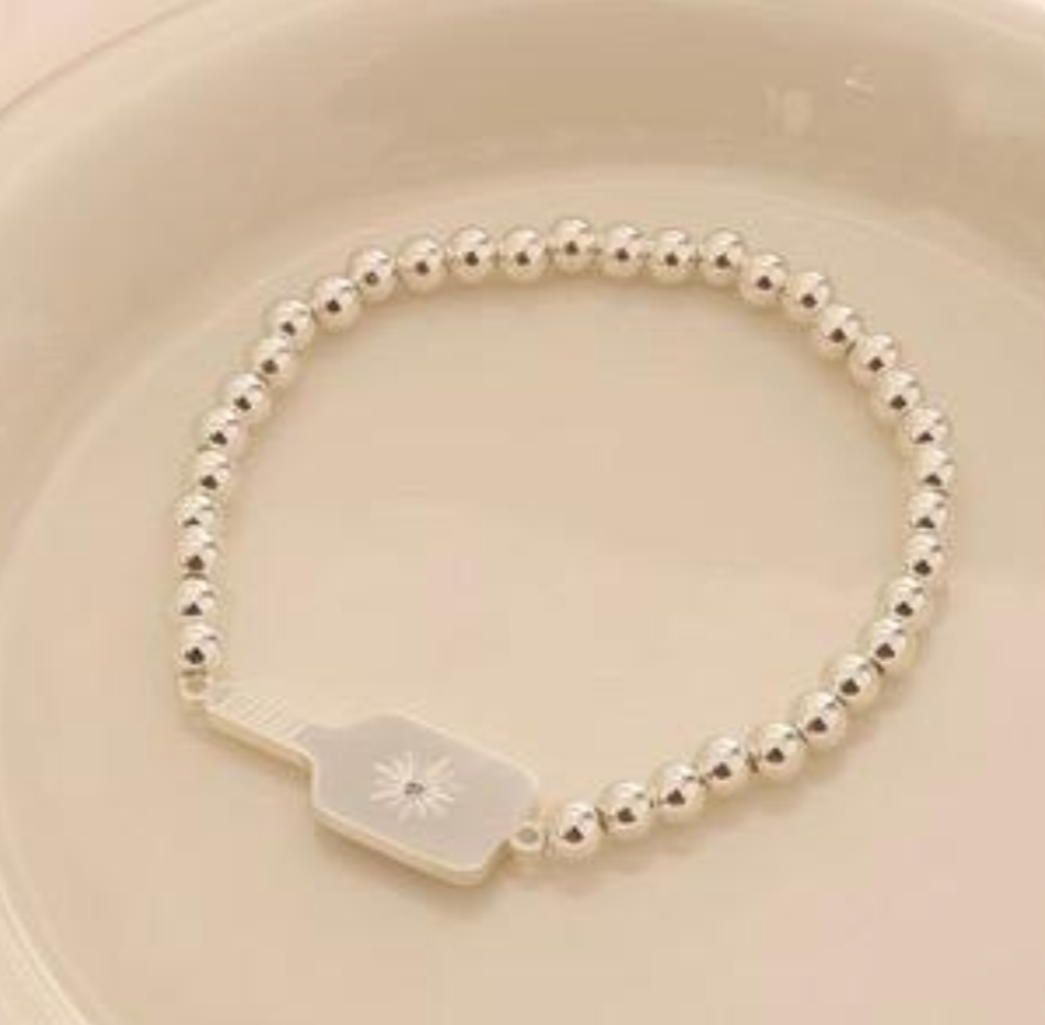 Picklebelle Silver beaded stretch bracelet with a pickle ball paddle on a beige background