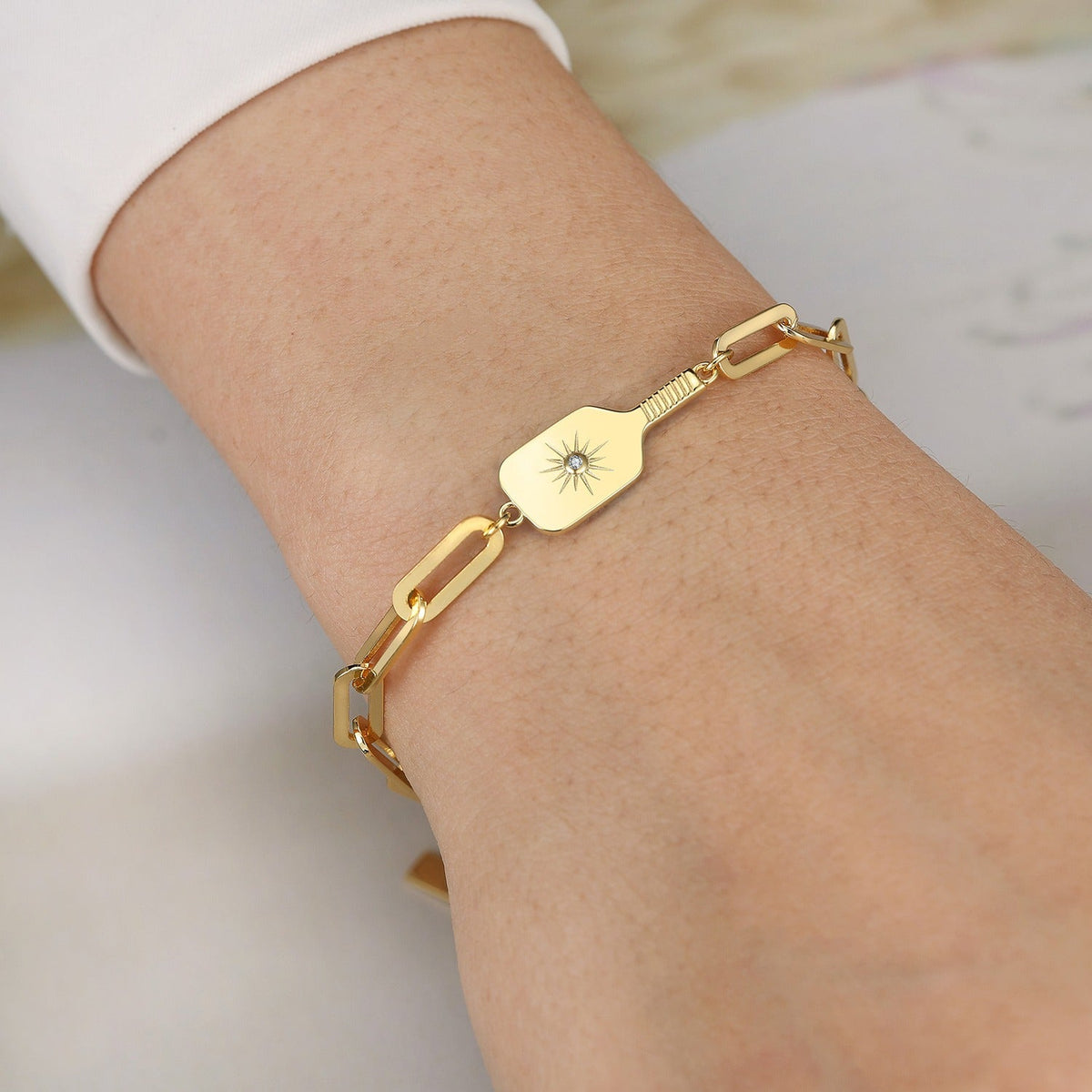 Gold bracelet with a unique pickleball paddle design with starburst crystal on a wrist