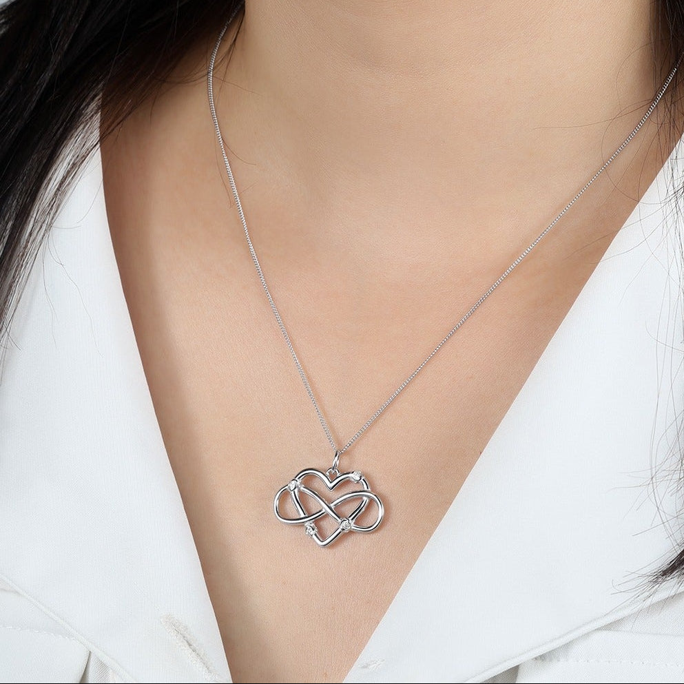 Silver necklace with a heart-shaped and infinity symbol pendant on a model