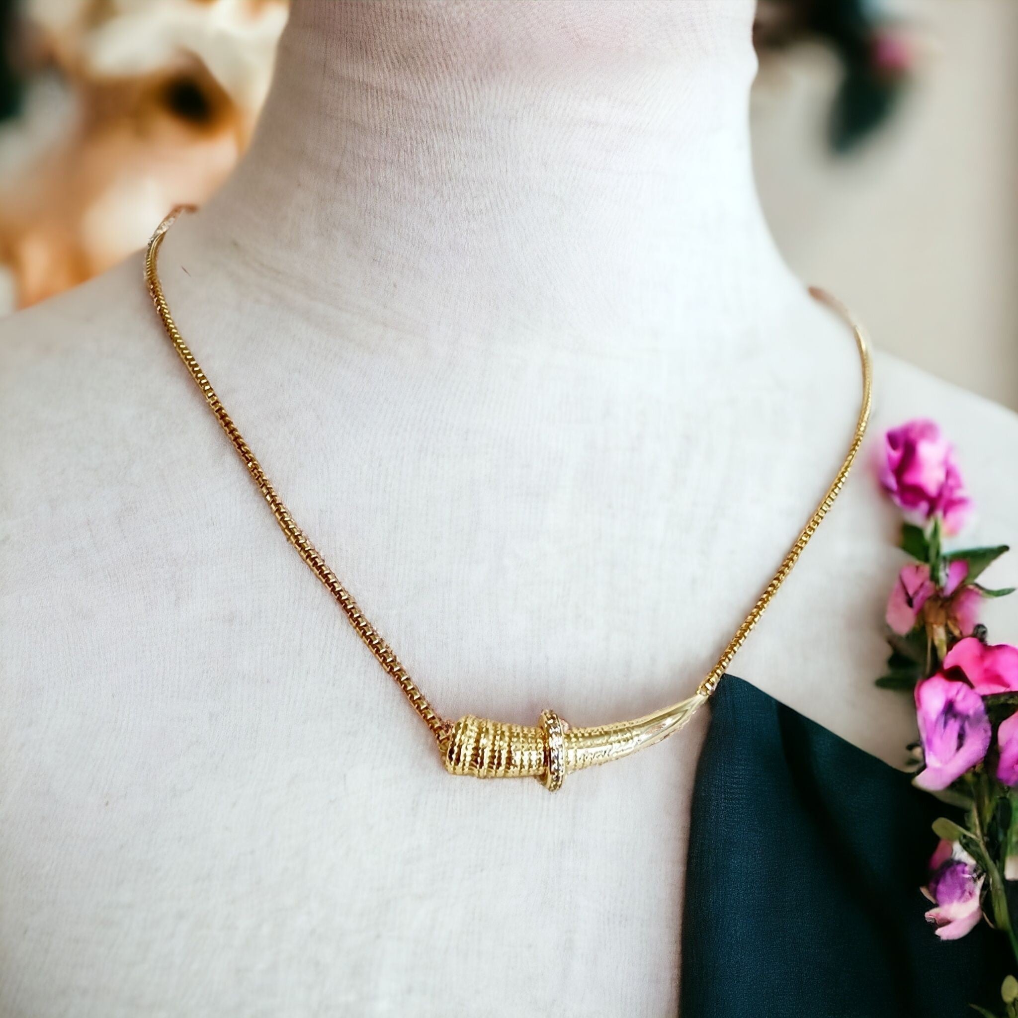 Gold horizontal horn necklace on a mannequin