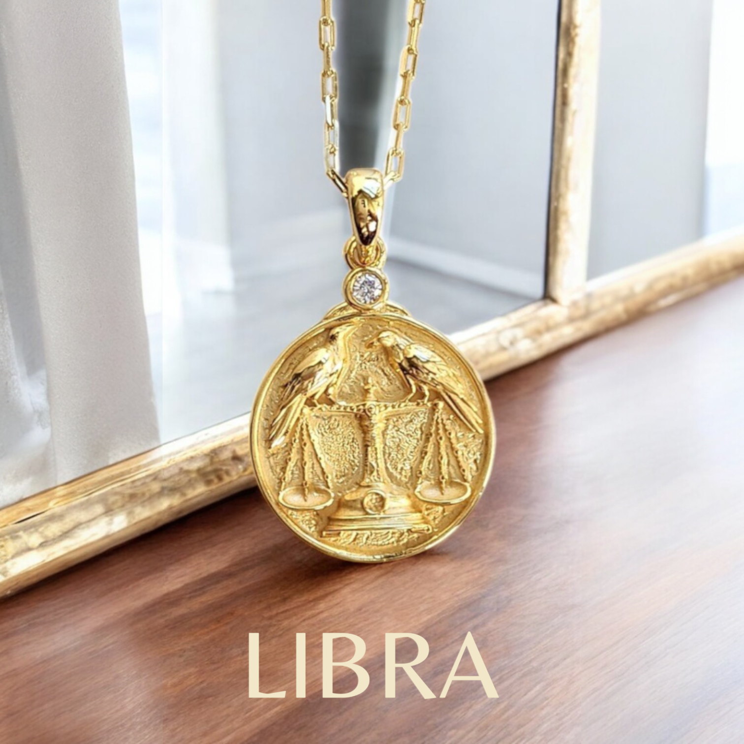 Gold Libra zodiac pendant necklace on a wooden surface with a blurred background