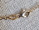 Gold bracelet with clasp on a textured gray background