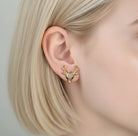 Gold deer-shaped earring worn by a person with blonde hair.