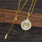 Gold and silver necklace with a Zodiac Cancer crab pendant on a wooden surface
