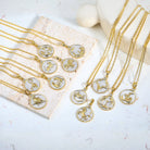 Gold necklaces with Gold and Silver zodiac pendants on a light surface
