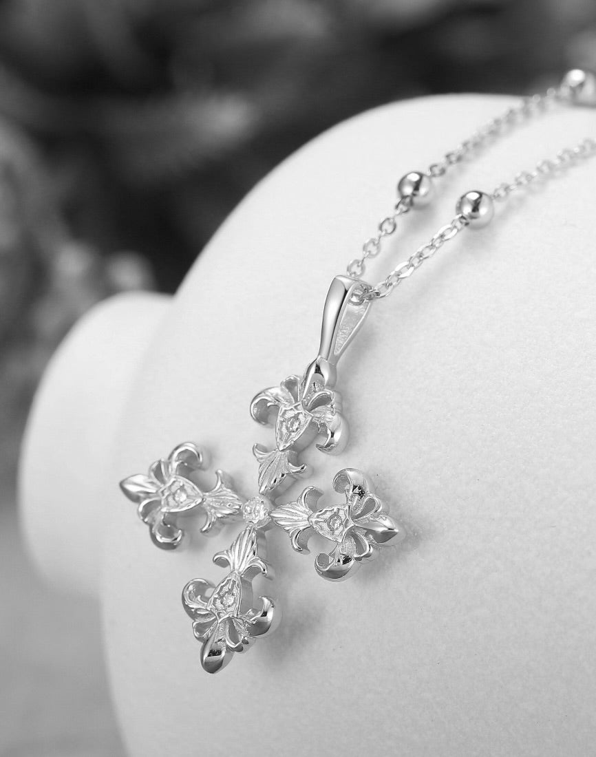 Saints and Saviors Silver necklace with a fleur de lis  pendant on a white stand 