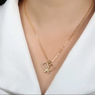 Gold necklace with a pickle ball paddle pendant on a model wearing a white shirt.
