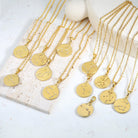 Gold necklaces with zodiac pendants on a white surface