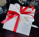 White gift box with a red ribbon on a dark surface
