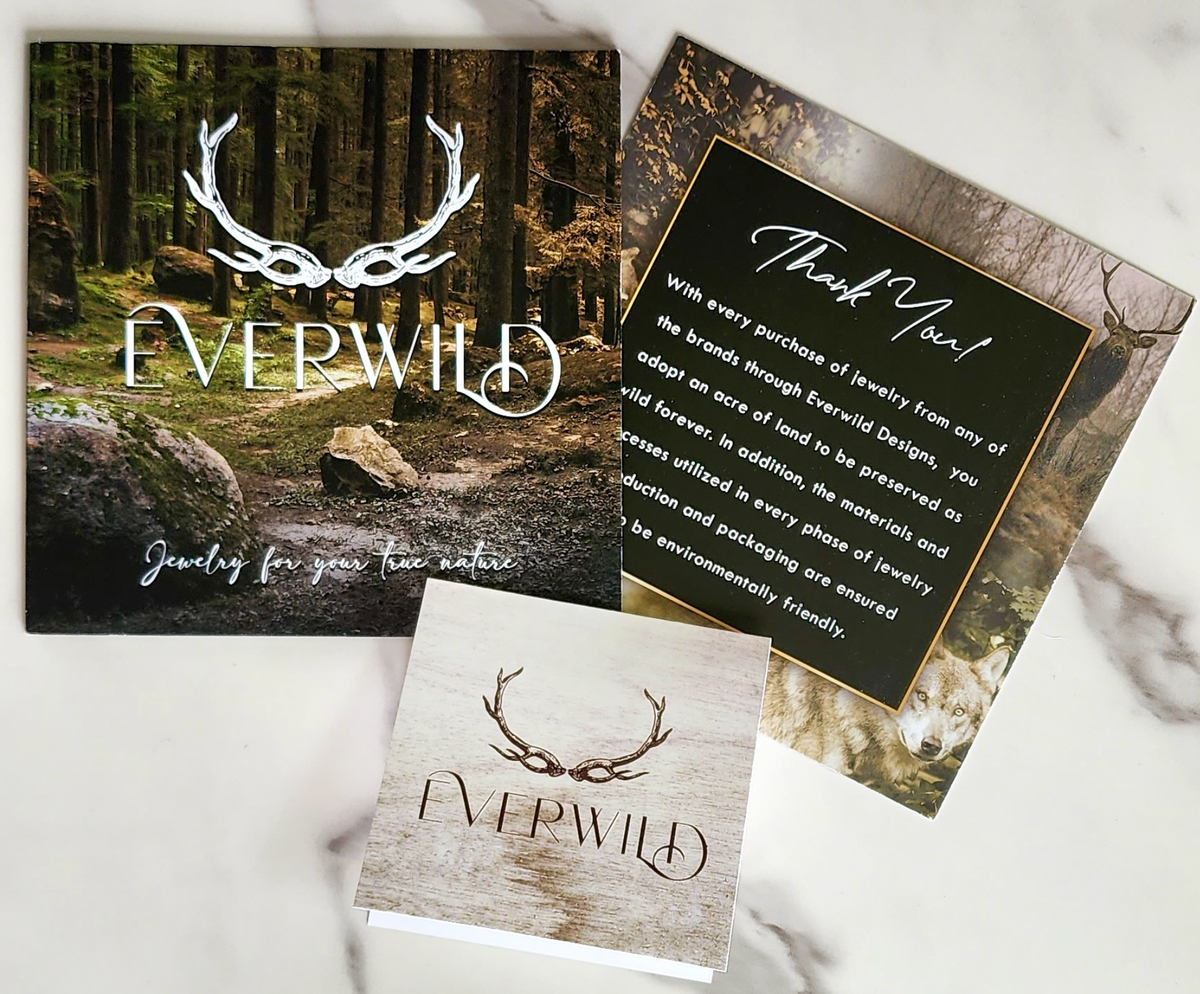 Everwild jewelry brand materials including cards and a sign on a marble surface.