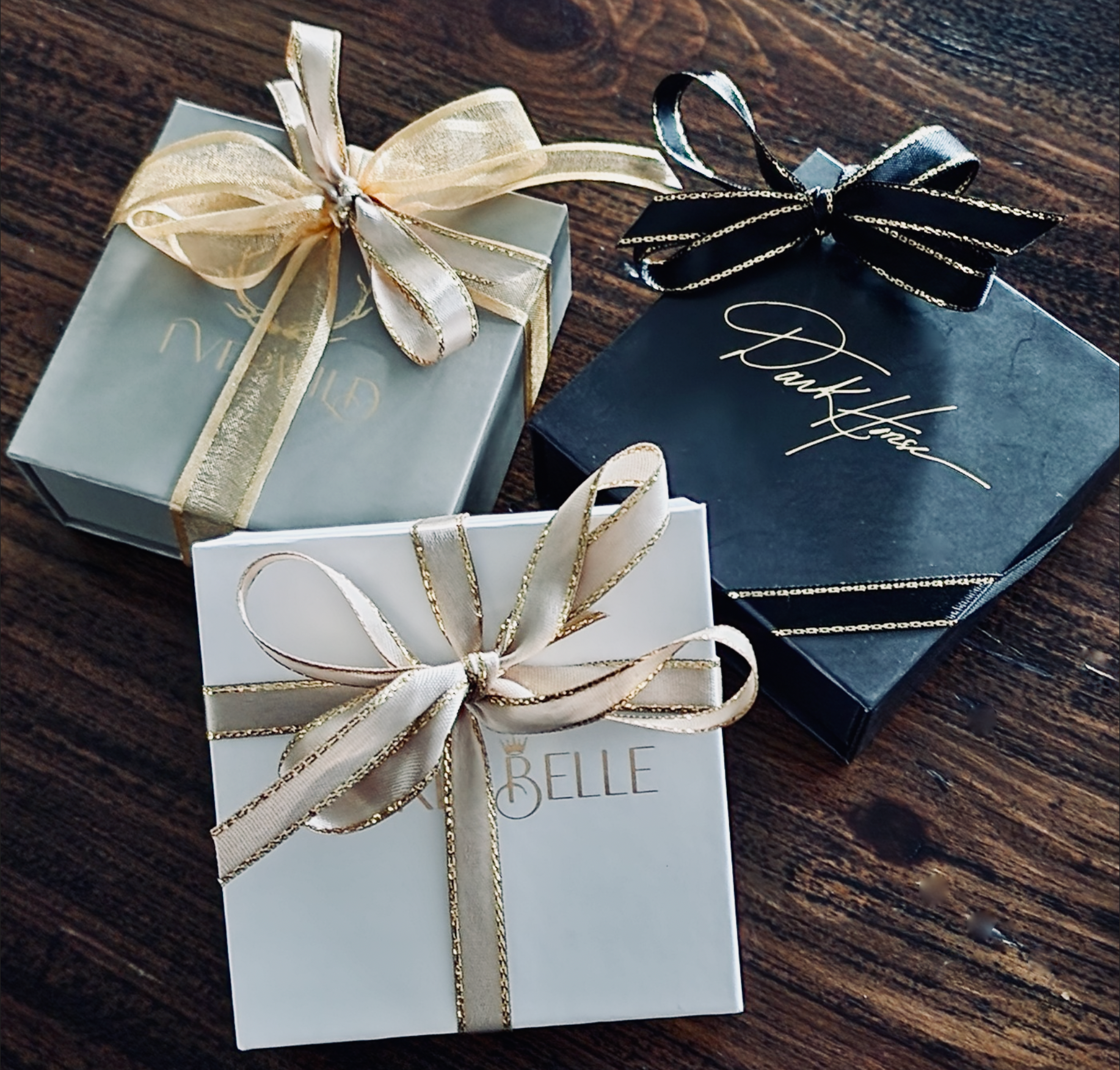 Three gift boxes with ribbons on a wooden surface