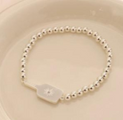 Picklebelle Silver beaded stretch bracelet with a pickle ball paddle on a beige background