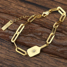 Gold bracelet with decorative pickleball paddle design and clip links on a wooden surface